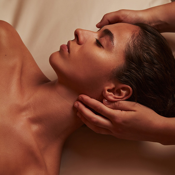 A woman with a relaxed expression getting a facial massage.