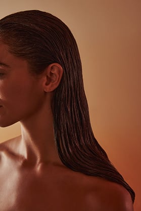 A woman with oil applied to her hair during a hair cleanse treatment.